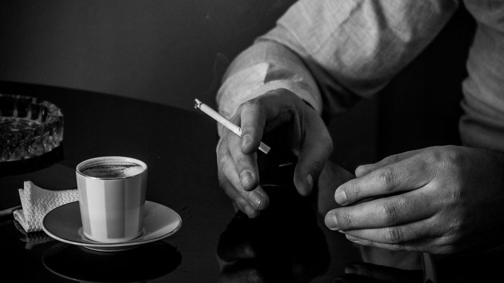 Руки Ашота с сигаретой, чашка с армянским кофе на столе